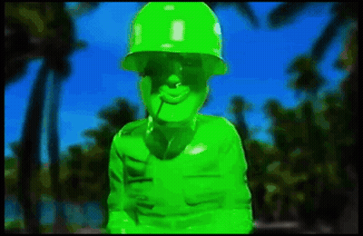 Green Soldier With Cigarette Standing In Front Of Palm Tree GIF