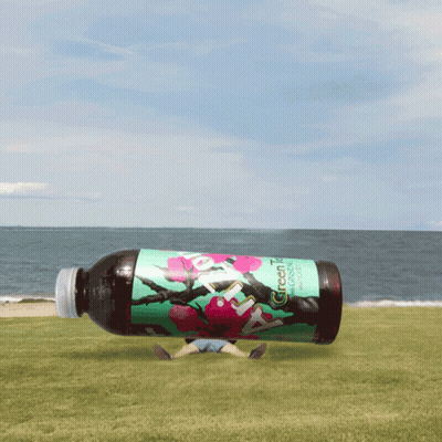 Green Tea Bottle Floating Above Beach GIF