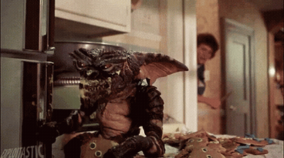 Gremlin Eating Gingerbread Cookies In Front Of Glotastic Refrigerator GIF