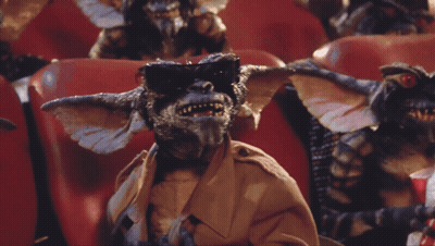 Gremlins Sitting In Red Chairs Eating Popcorn GIF