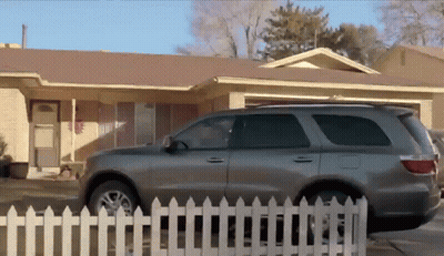 Grey SUV Parked In Front Of White Picket Fence GIF