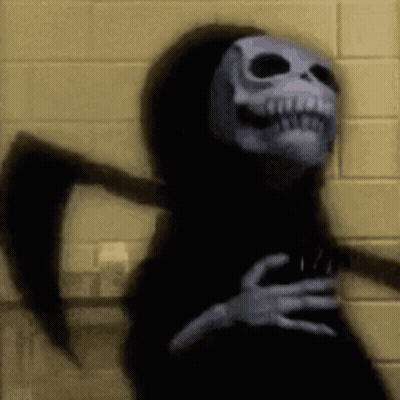 Grim Reaper With Scythe In Front Of Yellow Brick Wall GIF