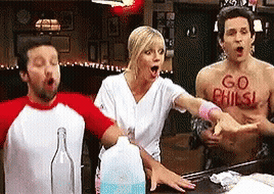 Group Around Table With Man Wearing Go Phils Shirt GIF