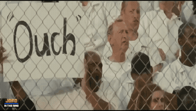 Group Behind Chain Link Fence Holding Ouch Signs GIF