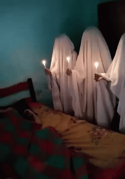 Group Covered In White Sheets Holding Candles In Front Of Bed GIF
