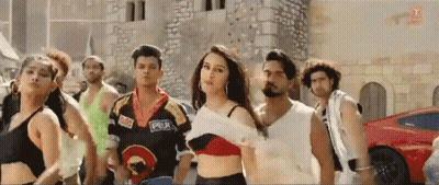 Group Dancing In Front Of Red Car And Brick Building GIF