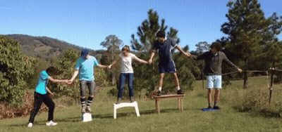Group Holding Hands Standing On Chairs GIF
