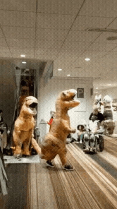 Group In Dinosaur Costumes Walking Down Hallway GIF