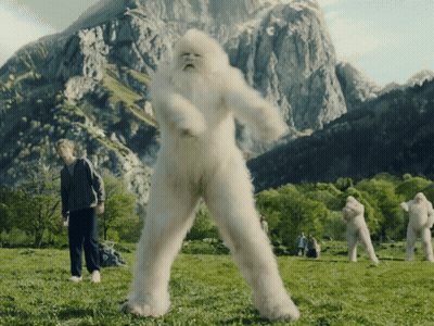 Group In Grassy Field With Mountains And Bigfoot Costume GIF