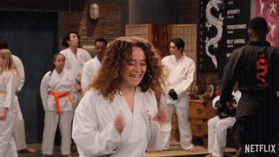Group In Karate Uniforms Dancing In Front Of Netflix Sign GIF