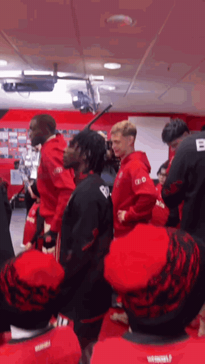 Group In Red And Black Shirts Standing In Room GIF
