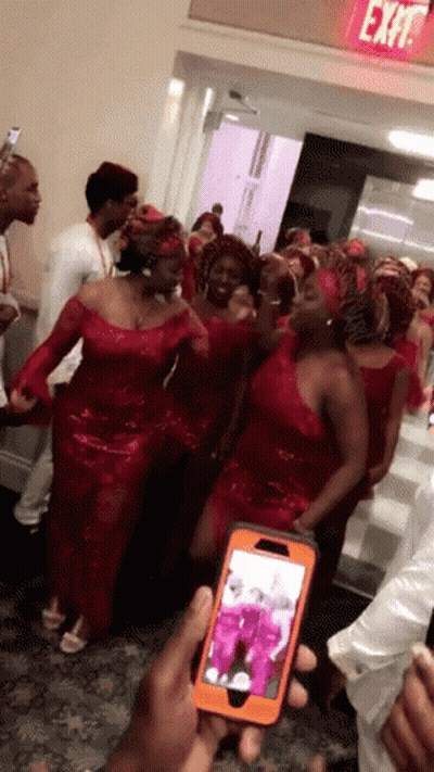 Group In Red Dresses In Front Of Exit Sign GIF