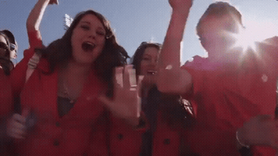 Group In Red Jackets Cheering With Hands Up GIF