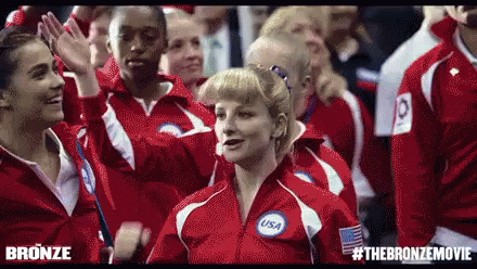Group In Red Jackets Standing In Crowd GIF