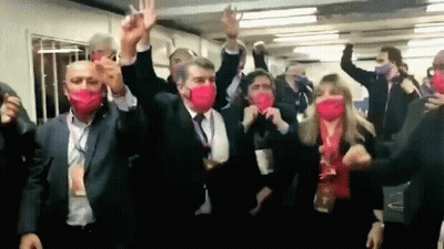 Group In Red Masks Dancing With Arms In Air GIF