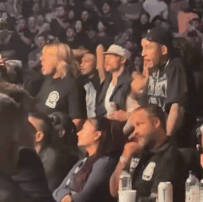 Group In Stadium With Man In Black Shirt Saying MK GIF