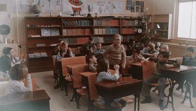 Group Of Children In Classroom With Merry Christmas Sign GIF