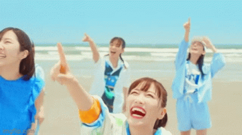 Group Of Girls Laughing And Pointing At Sky On Beach GIF