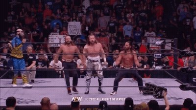 Group Of Men In Wrestling Ring With Too Sweet Cosplay Sign GIF