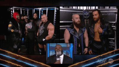 Group Of Men Next To Man In Suit With AEW Logo GIF