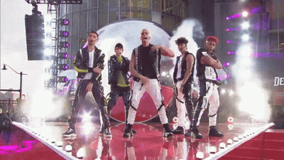 Group Of Men On Stage With Sign Saying De GIF