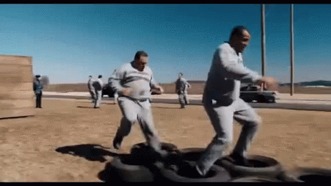 Group Of Men Playing With Tires In Desert GIF