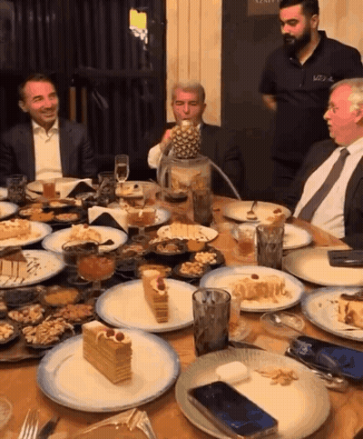 Group Of Men Sitting At Table With Food And Drinks GIF