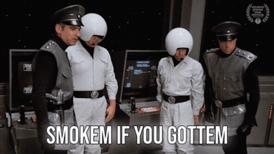 Group Of Men Standing In Front Of Arcade Machine Saying Smokem If You Gottem GIF