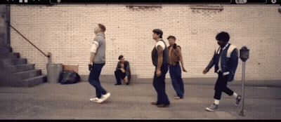 Group Of Men Walking Past Man Sitting On Sidewalk GIF