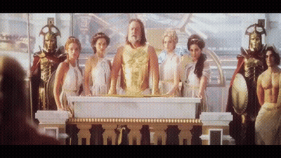 Group Of People Around Podium With Man In Gold Vest GIF
