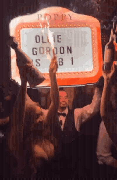Group Of People Dancing In Front Of Poppy Sign GIF