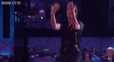 Group Of People Dancing On Stage In Front Of BBC One Sign GIF
