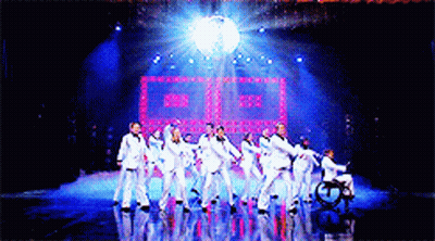 Group Of People Dancing On Stage With Disco Ball GIF