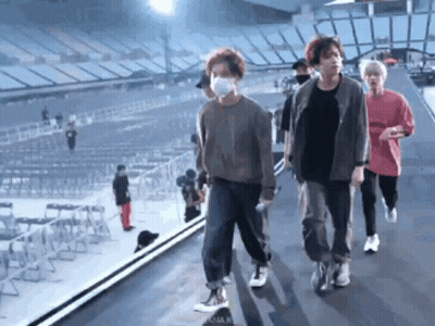 Group Of People In Face Masks Walking On Stage In Stadium GIF