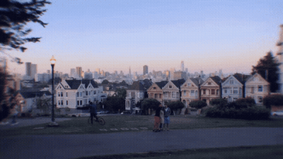 Group Of People In Front Of Row Of Houses With City Skyline GIF