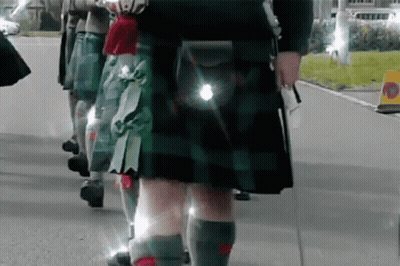 Group Of People In Kilts Walking Down Street GIF