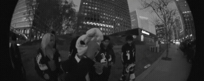 Group Of People On Sidewalk In Front Of Tall Buildings GIF