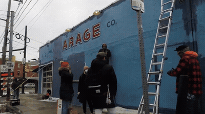 Group Of People Painting Blue Building Saying Arage Co GIF