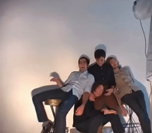 Group Of People Posing For Picture In Room With White Wall GIF