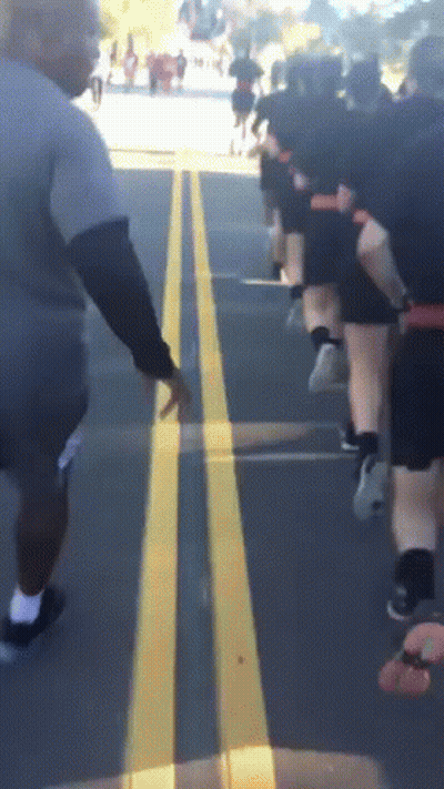 Group Of People Running On Street With Yellow Line GIF