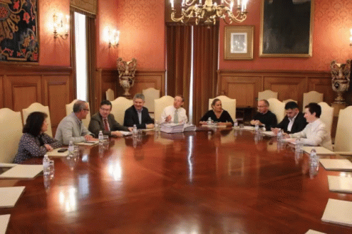 Group Of People Sitting Around Large Wooden Table In Conference Room GIF