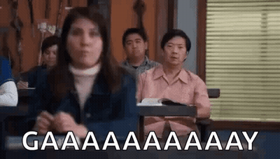 Group Of People Sitting At Desks In Classroom With Woman Standing In Front GIF