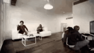 Group Of People Sitting In Living Room With Couch And Table GIF