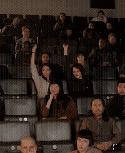 Group Of People Sitting In Theater With Letter H GIF