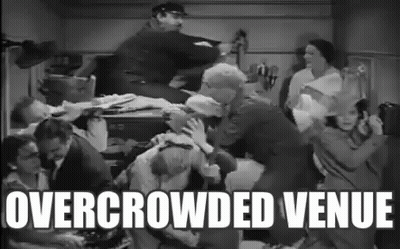 Group Of People Standing Around Table Overcrowded Venue GIF