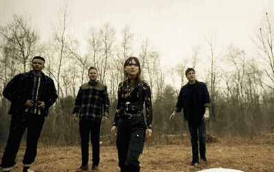 Group Of People Standing In Field With Trees GIF
