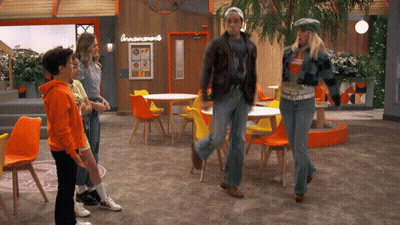 Group Of People Standing In Front Of Cinnamon Roll Sign GIF