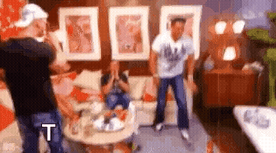 Group Of People Standing In Living Room With Couch And Table GIF