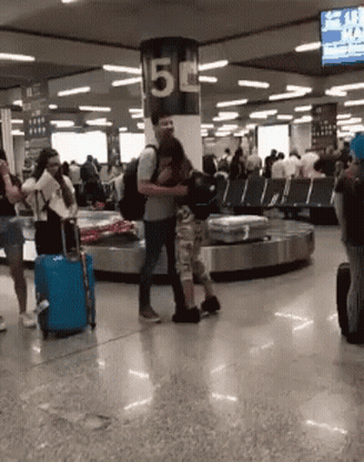 Group Of People Standing In Room With Sign Saying 5 GIF