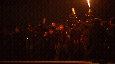 Group Of People Standing On Stage With Large Fire GIF